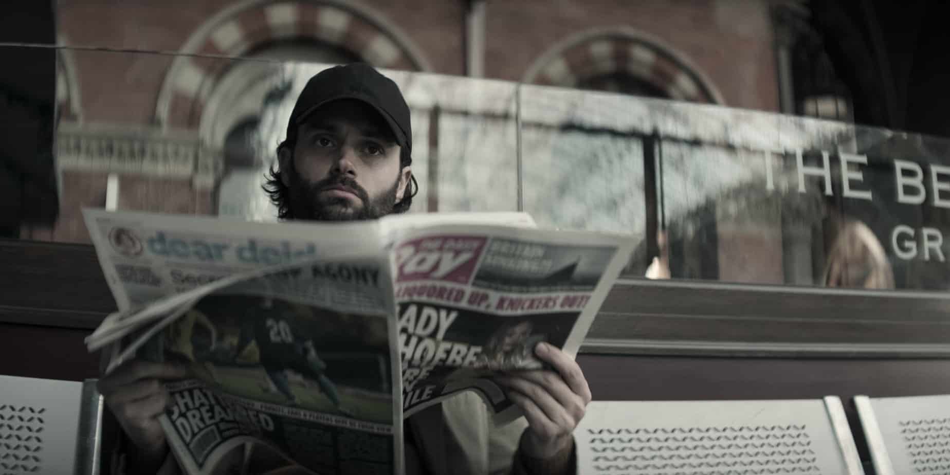 Ypu season 4 quotes from Joe. Joe looking over a newspaper, wearing a baseball cap and a full beard.