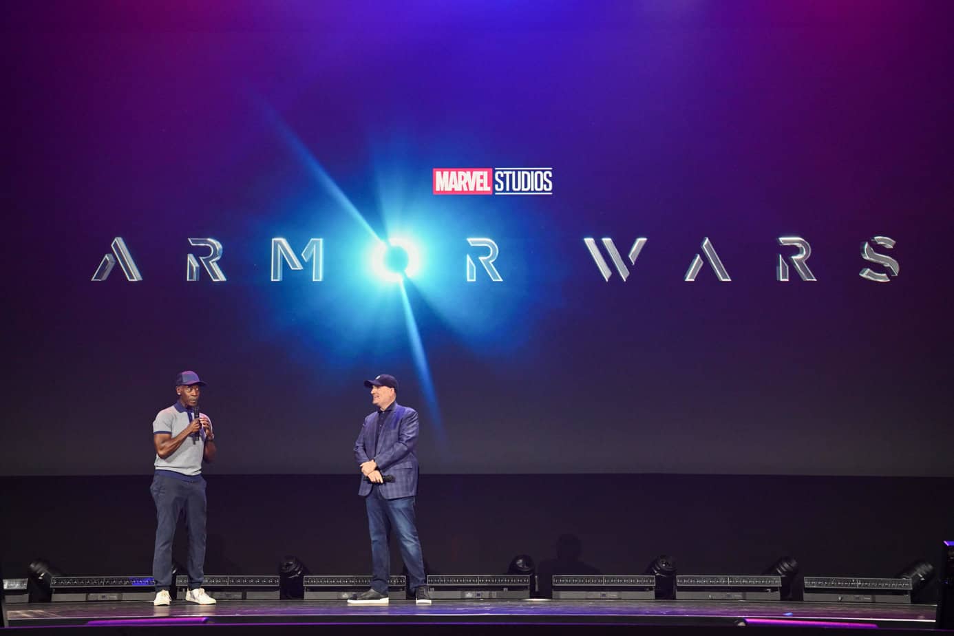 Don Cheadle and Kevin Feige on stage during the Marvel Studios panel at D23 Expo 2022 with the Armor Wars logo behind them.