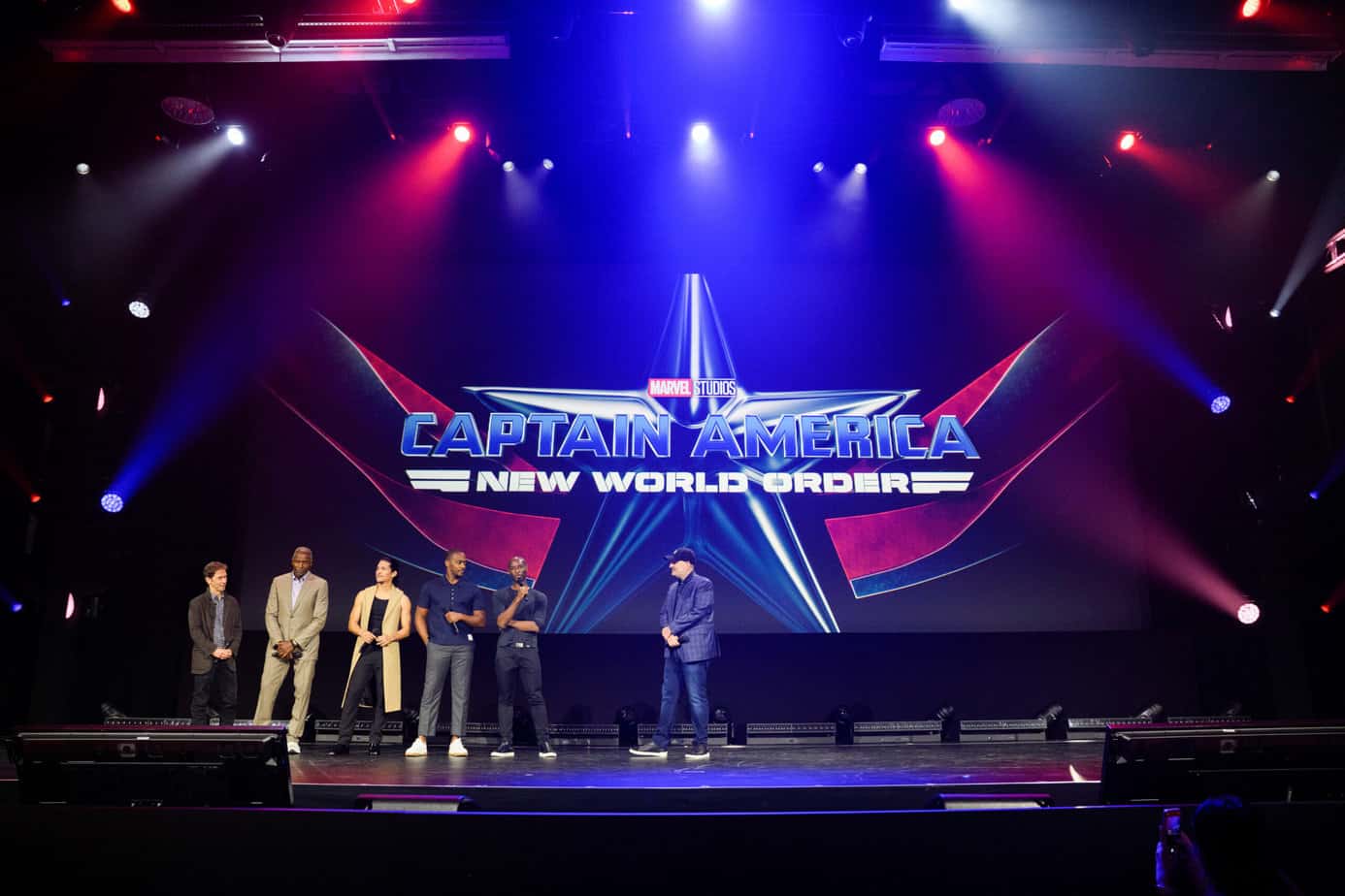 The cast of Captain America New World Order on stage during the Marvel Studios panel at D23 Expo 2022 with the film's logo behind them.