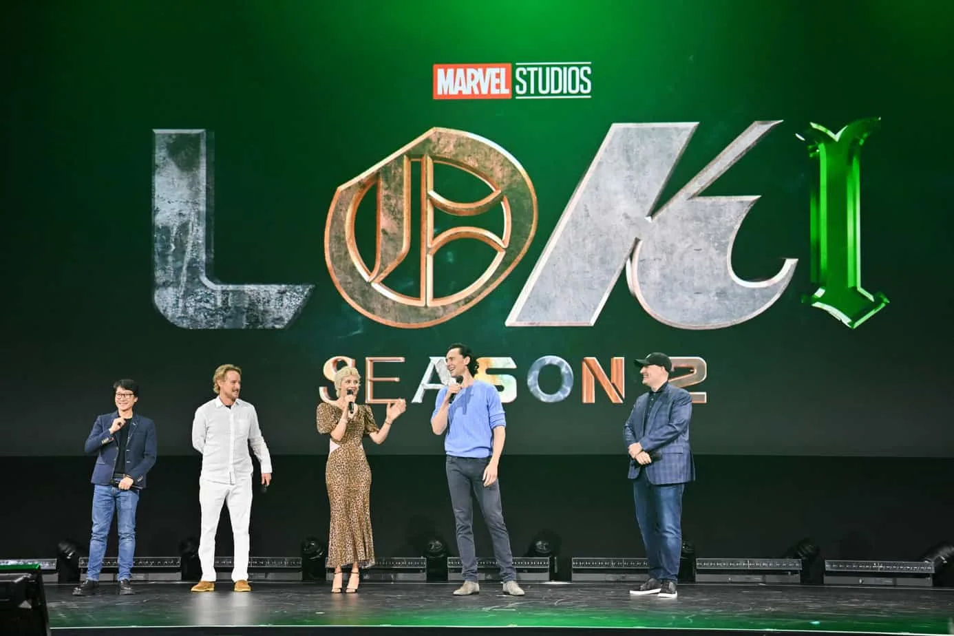 The cast of Loki Season 2 on stage during the Marvel Studios panel at D23 Expo 2022 with the Loki logo behind them.