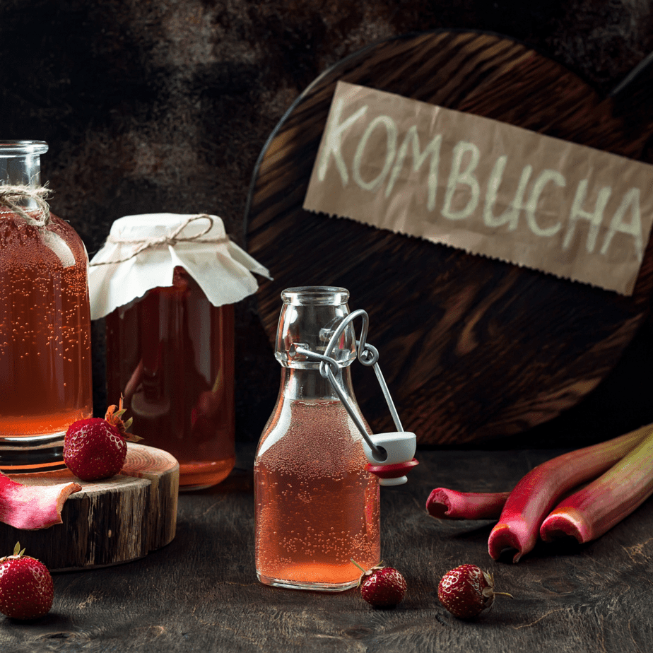 Kombucha bottles and rhubarb and strawberries on a wood table Spoilers without context glass onion