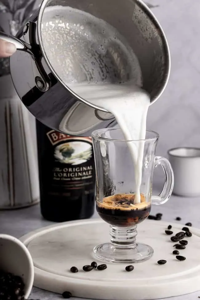 valentines latte idea baileys latte. Milk and baileys being poured into a coffee cup.